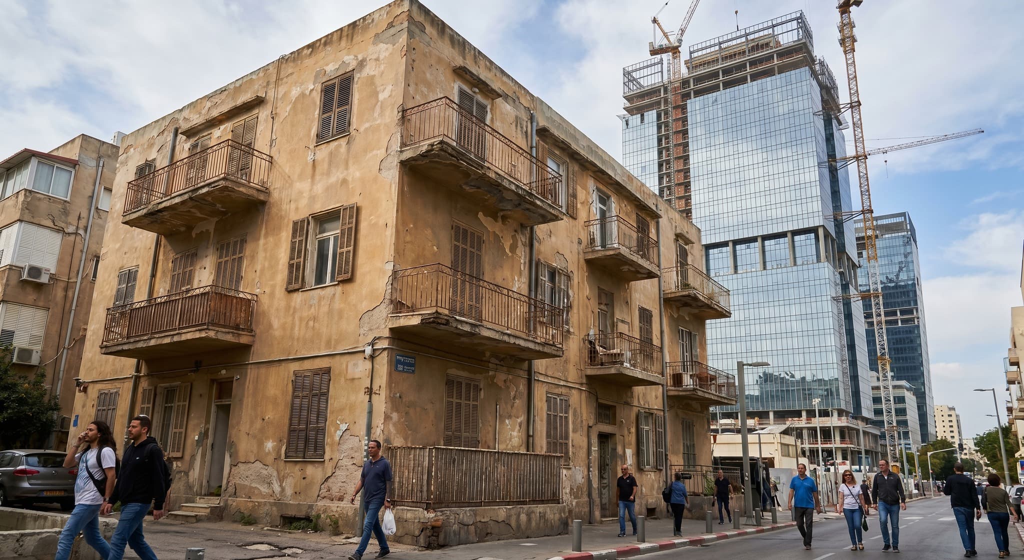 בניין מגורים ישן ומוזנח מול מגדל חדש ברקע — המחשה לתקדים מע"מ על זכויות בנייה בשכירות מוגנת